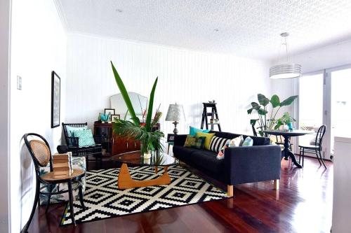 uma sala de estar com um sofá, uma mesa e cadeiras em Margaret House ~ Circa 1930 em Coffs Harbour