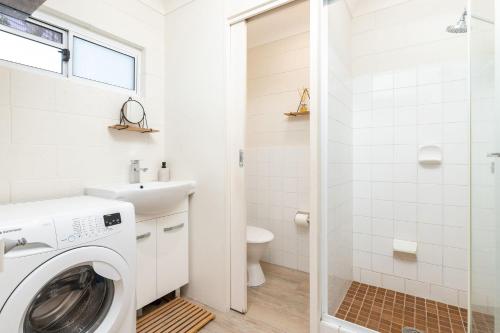 a white bathroom with a washer and dryer at Aloha At Blueys in Blueys Beach