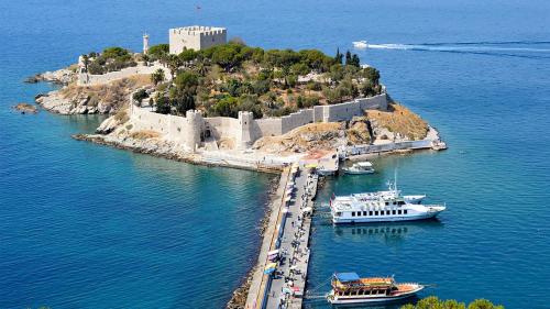 庫薩達斯的住宿－Kuşadası Apart Dairelerimiz，一座拥有城堡和水中船只的岛屿
