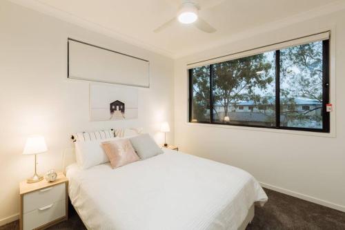 um quarto com uma cama branca e uma grande janela em Spacious Modern and Cozy 3BD Townhouse at Great Location em Gold Coast