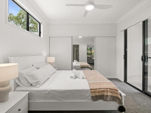 a white bedroom with a bed and a window at Newly Furnished Spacious 3BR Townhouse at GC in Gold Coast