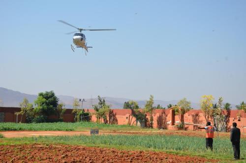 a helicopter flying over a field with two men at Vijayshree Resort, Hampi in Hampi