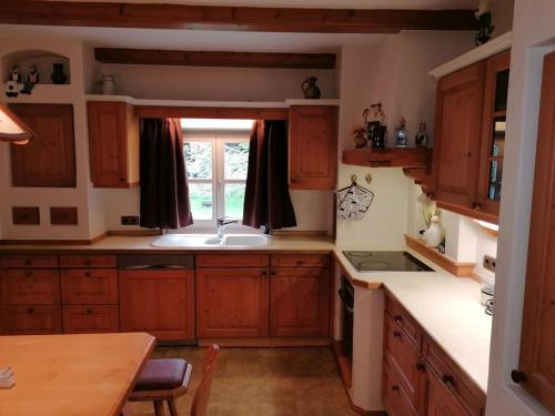 eine Küche mit Holzschränken, einem Waschbecken und einem Fenster in der Unterkunft Ferienwohnung Helli in Teisendorf