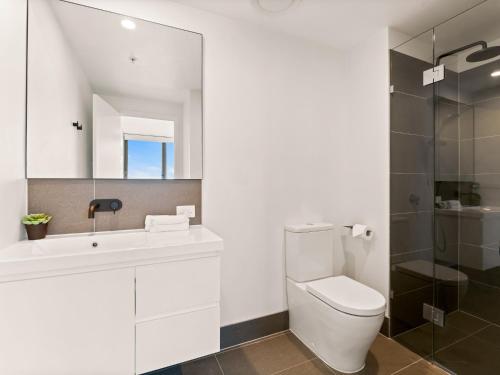 a bathroom with a toilet and a sink and a mirror at Heart of the Valley Chic High Level 2BR Apartment in Brisbane