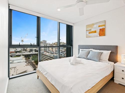 a bedroom with a large white bed and large windows at Heart of the Valley Chic High Level 2BR Apartment in Brisbane