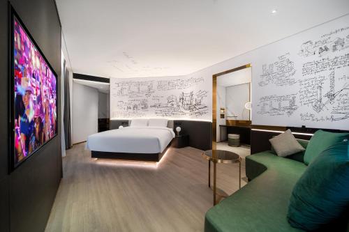 a bedroom with a bed and a green couch at CitiGO Hotel Shenzhen Shekou Cruise Center Seaview Near Taizi Bay K11 in Shenzhen