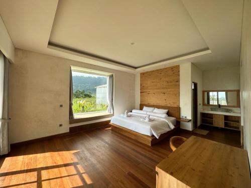 a bedroom with a bed and a large window at Agusta Lake View Bedugul in Pabean Buleleng