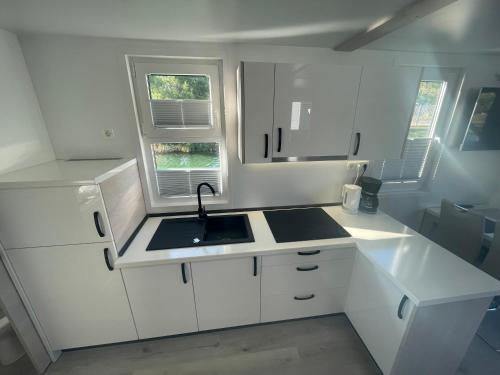 a kitchen with white cabinets and a sink and two windows at Floating sea house - PULA 1 in Pula