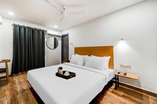 a bedroom with a large white bed and a mirror at Townhouse De Alphabet Tirupati in Tirupati