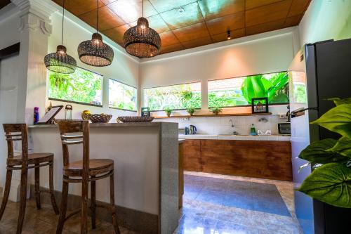 a kitchen with a bar with stools and windows at Villa MONTI - LEGIAN - SEMINYAK - Lovely 2 Bedroom Villa - Great Location ! in Seminyak