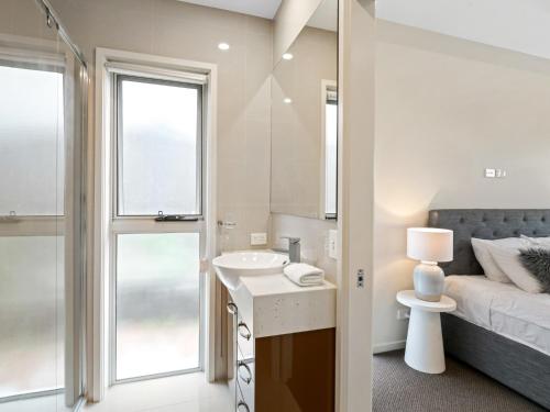 a bathroom with a sink and a bed and a mirror at Luxury Hilltop Brand-New 5BD Holiday Home in Brisbane