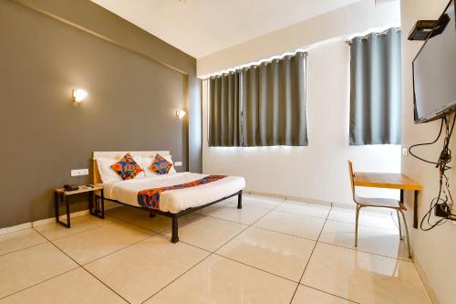 a bedroom with a bed and a table and a chair at FabHotel Kaviya in Ahmedabad