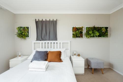 a bedroom with a white bed with two night stands at Spacious newly redecorated 5BD Family Home in Brisbane