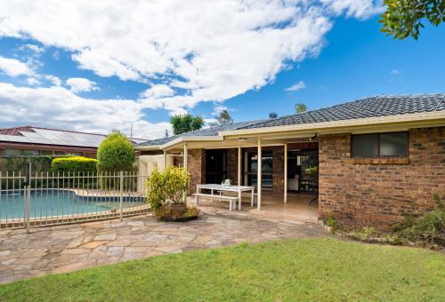 a brick house with a pool and a fence at Hobbit House Inspired 4BR cozy Fairytale Cottage in Brisbane