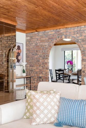 a living room with a couch and a brick wall at Hobbit House Inspired 4BR cozy Fairytale Cottage in Brisbane