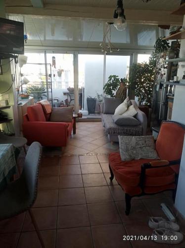 Il comprend un salon doté de canapés et de chaises. dans l'établissement Plage des catalans, à Marseille