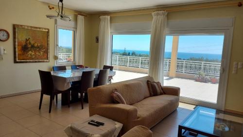 ein Wohnzimmer mit einem Sofa, einem Tisch und einem großen Fenster in der Unterkunft Magnificent View Villa in Alexandroupoli