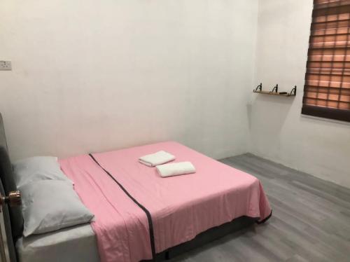 a room with a pink bed with two towels on it at Rasa Sayang Homestay Mersing in Mersing
