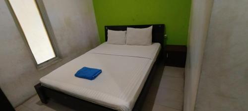 een klein bed in een kamer met een blauw kussen erop bij SPOT ON 92658 Wisma Parakita Syariah in Makassar