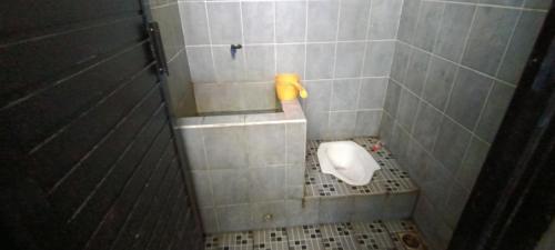 La salle de bains est pourvue de toilettes et d'un mur carrelé. dans l'établissement SPOT ON 92658 Wisma Parakita Syariah, à Makassar