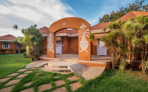 a house with an archway in front of a yard at Vijayshree Resort, Hampi in Hampi