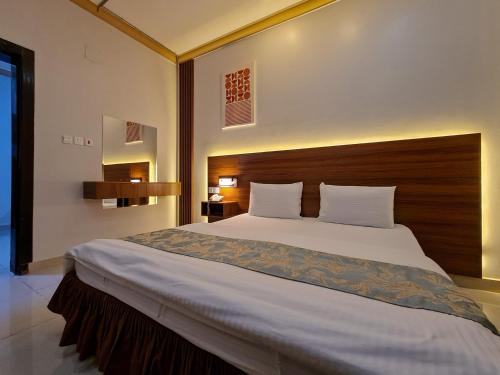 a bedroom with a large bed with a wooden headboard at Shams Alshate شمس الشاطئ in Buraydah