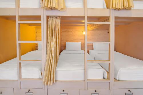 a room with two bunk beds with white pillows at Capital O 92559 Sweet Peach House in Senggigi