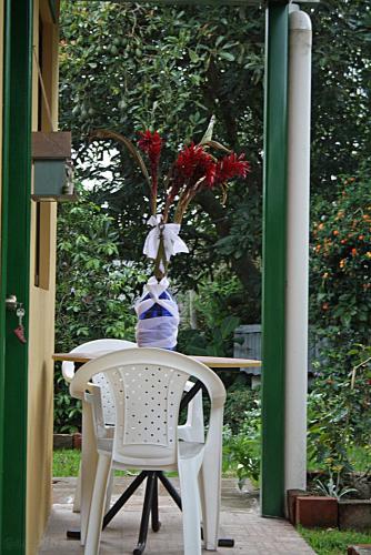 a table and a chair with a vase of flowers on it at Hostal Saint Mary´s Tababela in Tababela