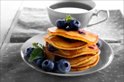 a plate of pancakes with blueberries and a cup of coffee at JW Marriott Mumbai Juhu in Mumbai