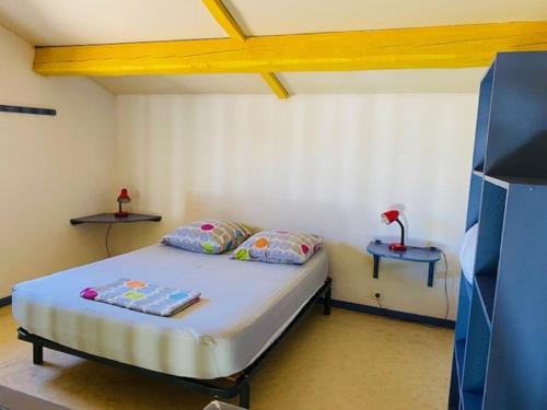 een kleine slaapkamer met een bed en twee tafels bij Location, piscine, animaux, jardin clôturé, parking, var, provence , wifi in Lorgues