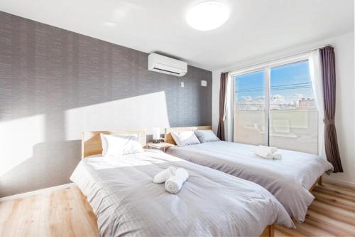 2 Betten in einem Zimmer mit einem großen Fenster in der Unterkunft THE SUN - Vacation STAY 14334 in Sapporo