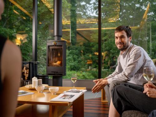 a man sitting at a table in a room with a wood stove at AYA Villa in Niseko