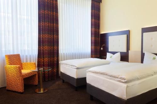 a hotel room with two beds and a chair at Best Western Hotel Augusta in Augsburg