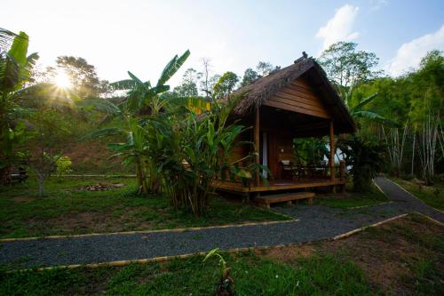 a small cabin in a forest with the sun shining at Naga Lodge in Luang Prabang