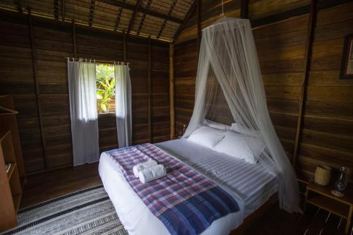 a bed with a canopy in a room with a window at Naga Lodge in Luang Prabang