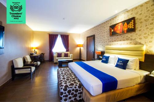 una habitación de hotel con una cama grande y una silla en Dafam Hotel Cilacap, en Cilacap