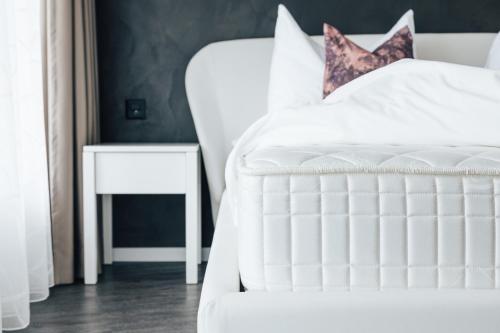 a bedroom with a white bed and a side table at CHRIStania in Fiesch