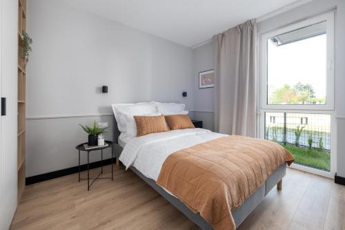 Un dormitorio blanco con una cama grande y una ventana en A Morze Las - apartament na Wyspie Sobieszewskiej en Gdansk