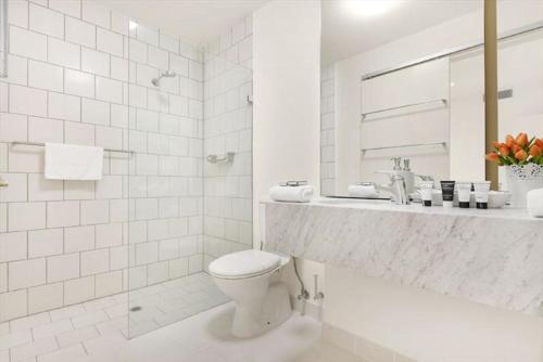 Baño blanco con aseo y lavamanos en StayCentral - Melbourne Central, en Melbourne