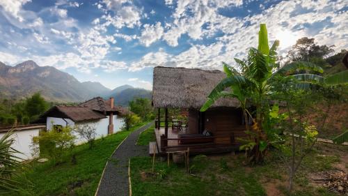 a small house with a thatched roof and a road at Naga Lodge in Luang Prabang