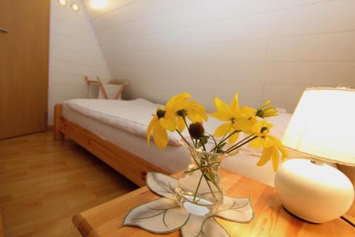 un jarrón con flores amarillas sobre una mesa con una cama en Finnhütte Nr.42 auf Mönchgut, en Gager