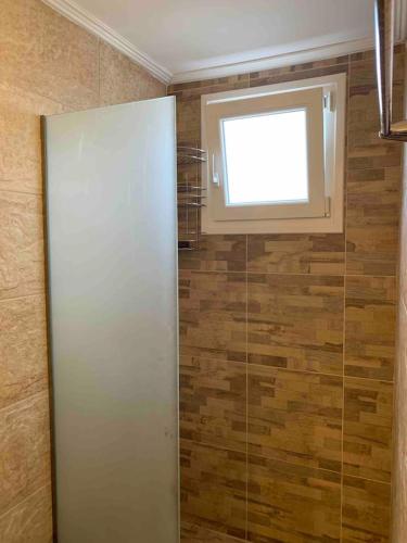 a bathroom with a window and a glass shower at Cleopatra's Cozy Cottage in Keramoti