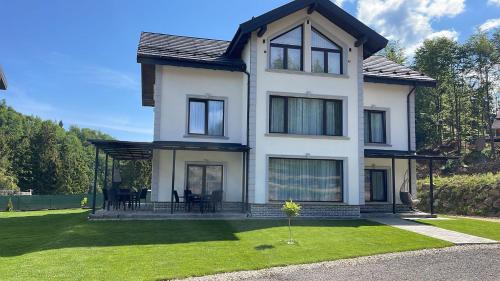 a large white house with a grass yard at Royal Alpin Crown in Cavnic