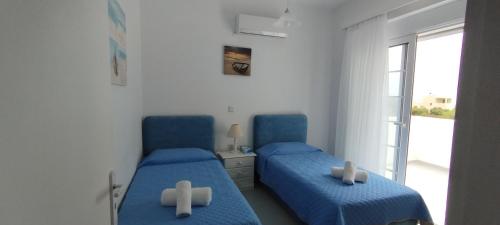 two blue beds in a room with a window at Aphrodite Villa Gennadi in Gennadi