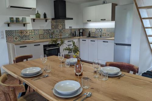 une table en bois avec des assiettes et des verres à vin dessus dans l'établissement Maison au bord de la rivière Aveyron - Bruniquel, à Bruniquel
