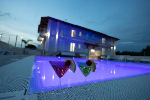 two wine glasses sitting on a table in front of a pool at Rosy's House in Scafati