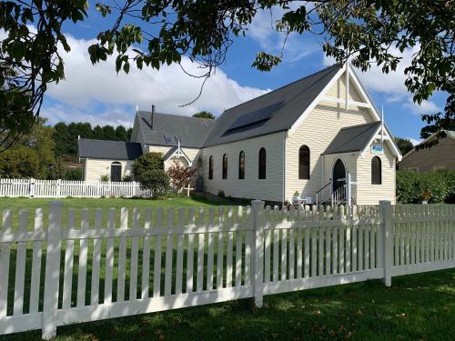 a white church behind a white picket fence at Angel Place Robertson in Robertson