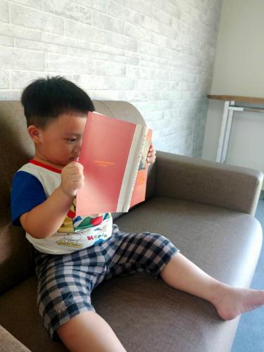 a young boy sitting on a couch reading a book at 山淺民宿 Yamasaki Old House in Taiping