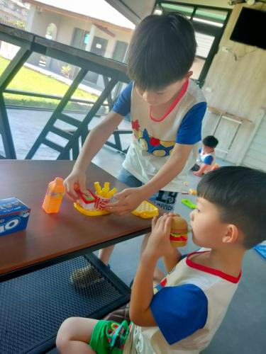 two young boys sitting at a table eating a hot dog at 山淺民宿 Yamasaki Old House in Taiping