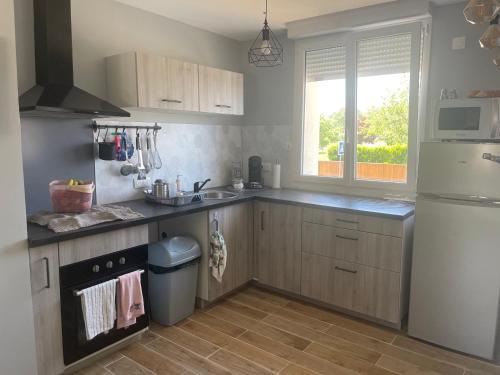 une cuisine avec des armoires en bois, un évier et une fenêtre dans l'établissement Maison 24h du Mans, à Moncé-en-Belin